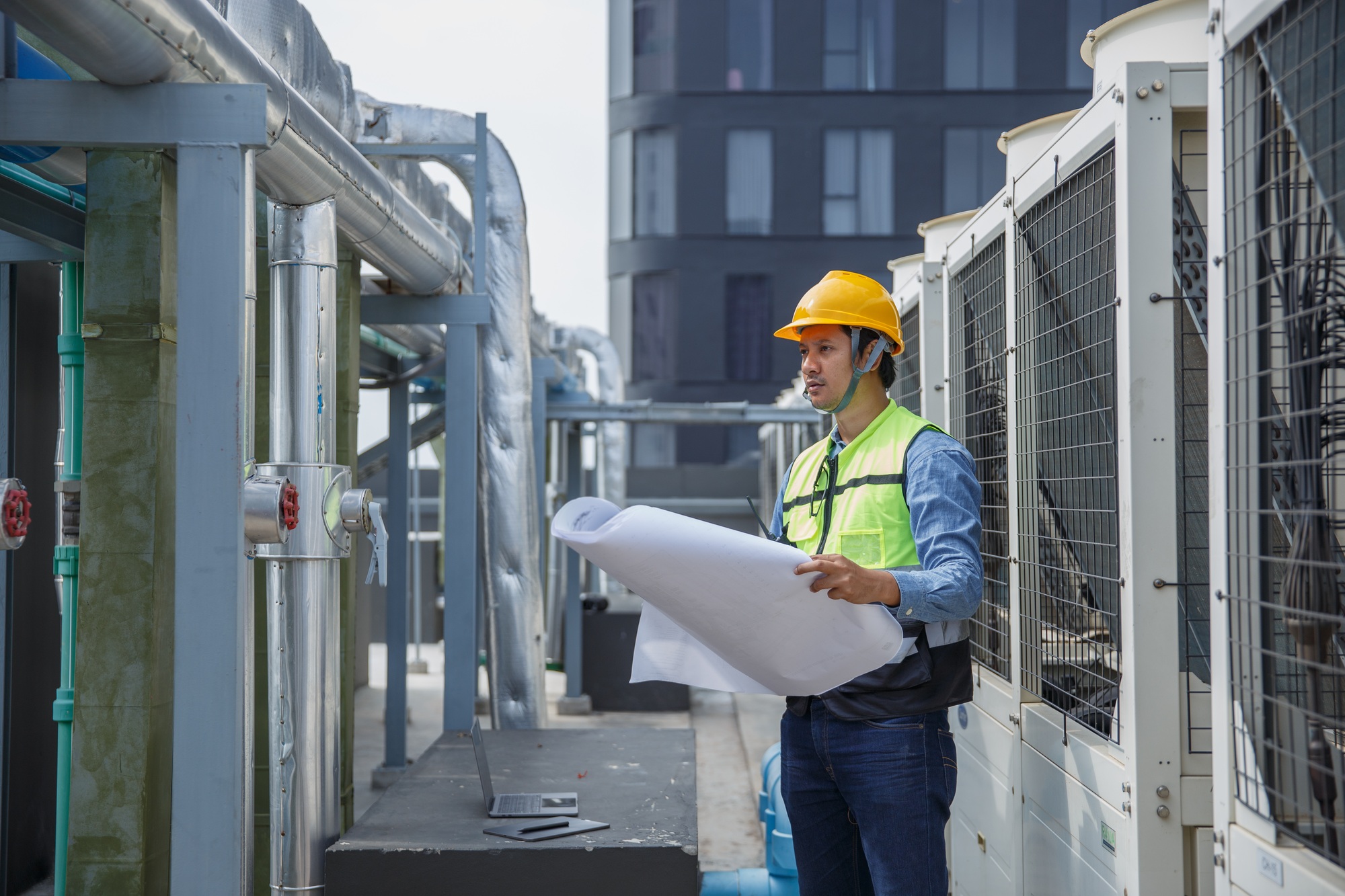 Male operator worker reading blueprint checking drawing plan cooling air piping HVAC